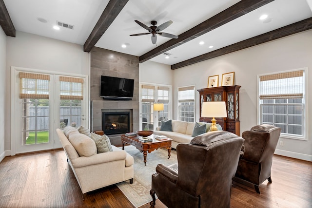 living room featuring a fireplace, wood finished floors, visible vents, baseboards, and beamed ceiling