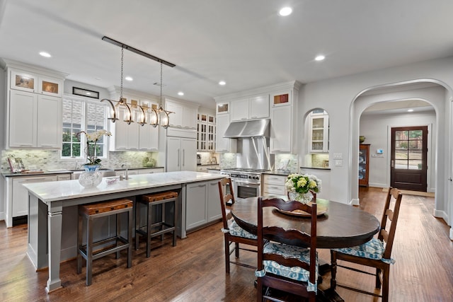 dining area featuring arched walkways, dark wood-type flooring, a wealth of natural light, and recessed lighting