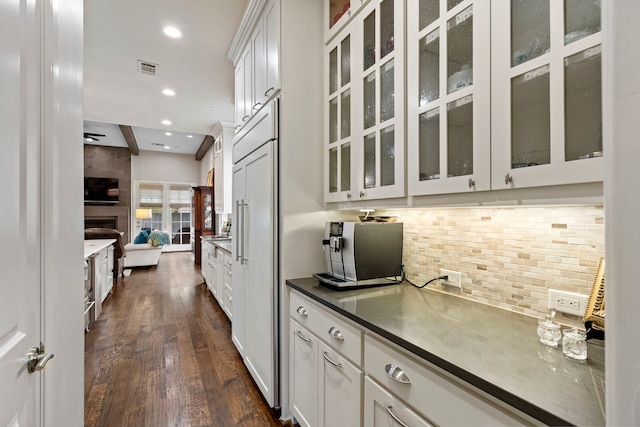 kitchen featuring glass insert cabinets, dark countertops, white cabinetry, and decorative backsplash