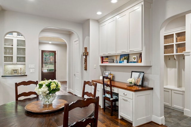 dining area featuring arched walkways, built in desk, dark wood-style floors, and recessed lighting