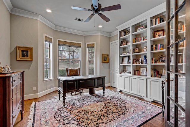 office space with ceiling fan, visible vents, baseboards, light wood-style floors, and crown molding