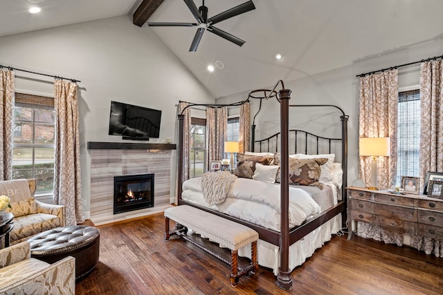 bedroom featuring dark wood-style flooring, beam ceiling, recessed lighting, a tiled fireplace, and high vaulted ceiling