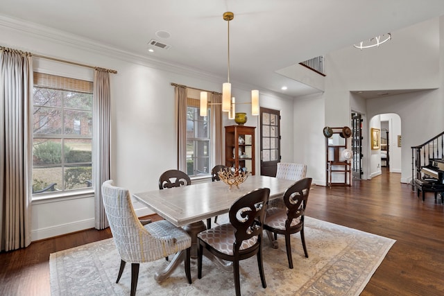 dining room featuring dark wood-style floors, visible vents, arched walkways, and ornamental molding