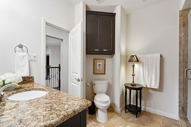 full bathroom featuring a stall shower, baseboards, vanity, and toilet