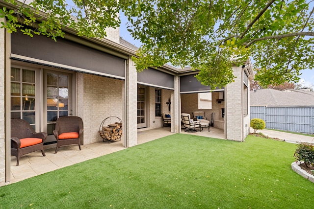 exterior space featuring a patio, brick siding, fence, a lawn, and a chimney