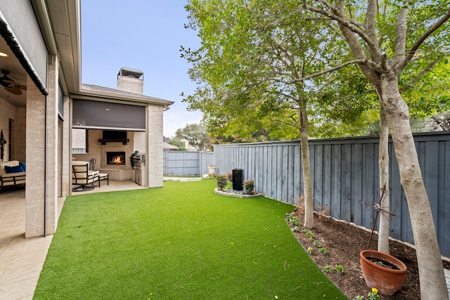 view of yard with a fenced backyard, a patio, and a lit fireplace