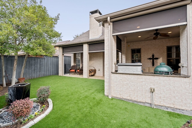 view of yard with exterior kitchen, a patio area, fence, and a ceiling fan