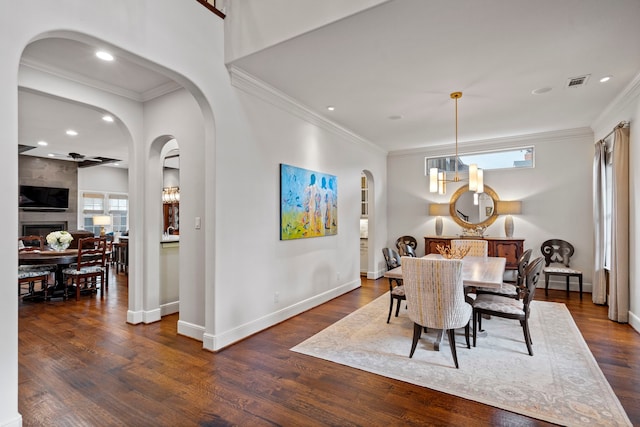 dining room with crown molding, arched walkways, visible vents, and dark wood finished floors