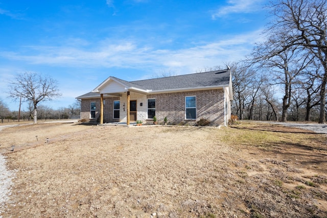 view of front of property with a shingled roof, a front lawn, and brick siding