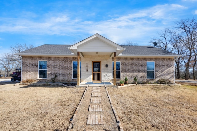 single story home featuring brick siding, roof with shingles, and a front lawn