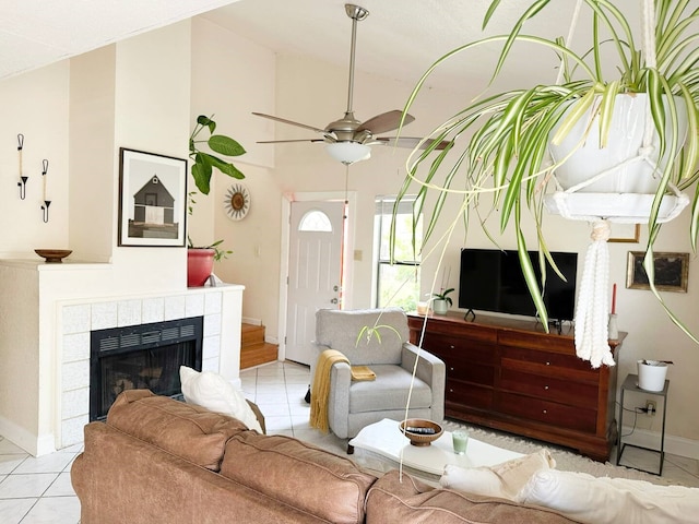 living room featuring a fireplace, light tile patterned flooring, vaulted ceiling, ceiling fan, and baseboards