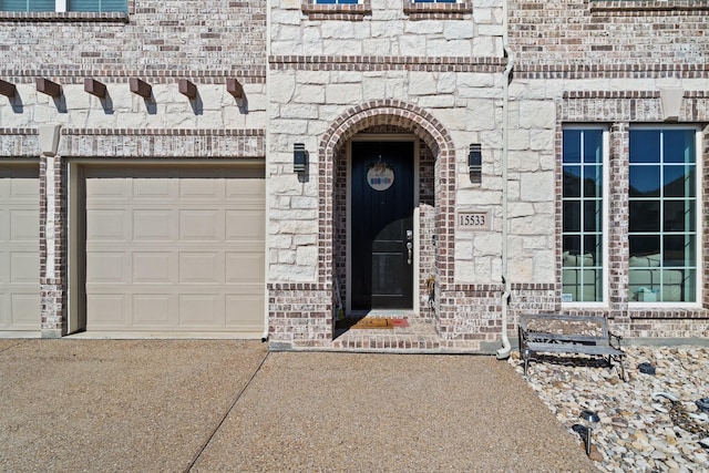 doorway to property featuring a garage and brick siding