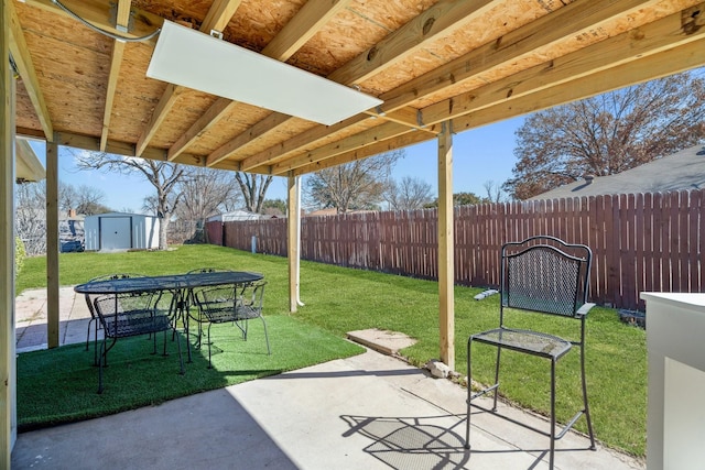 view of patio / terrace with outdoor dining space, a shed, a fenced backyard, and an outdoor structure