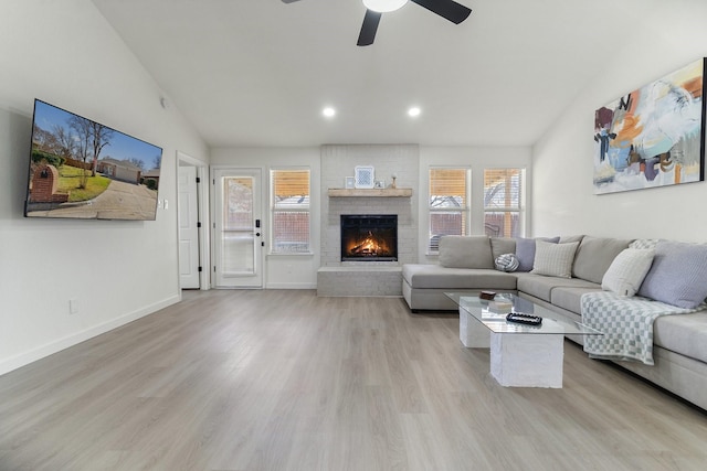 living area featuring baseboards, vaulted ceiling, light wood-type flooring, a fireplace, and recessed lighting