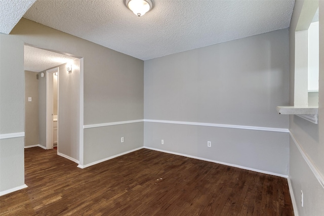 spare room with wood finished floors, baseboards, and a textured ceiling