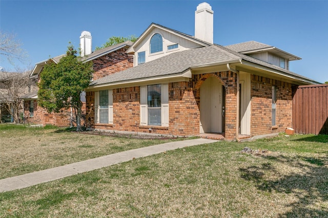 view of front of property with a front lawn, brick siding, and roof with shingles