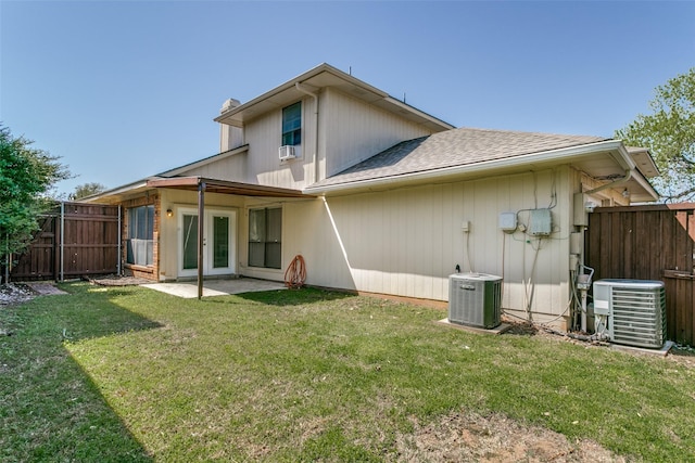 back of property featuring central air condition unit, fence, a lawn, and french doors