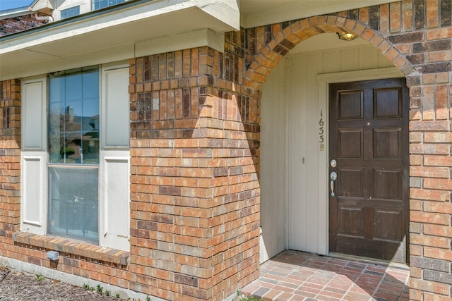 view of exterior entry featuring brick siding