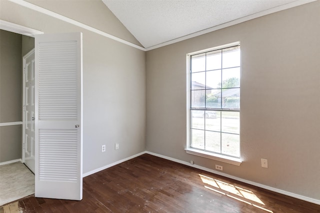 empty room with baseboards, hardwood / wood-style flooring, a healthy amount of sunlight, and vaulted ceiling