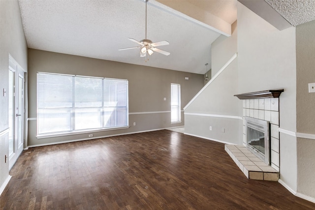 unfurnished living room with ceiling fan, lofted ceiling with beams, wood finished floors, and a tile fireplace