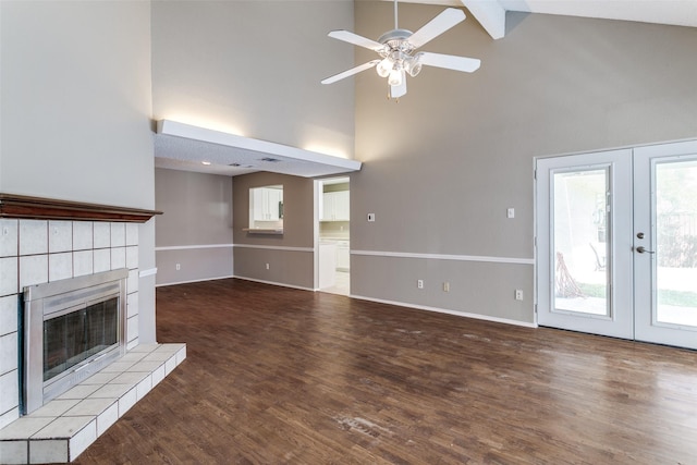 unfurnished living room featuring wood finished floors, baseboards, a ceiling fan, french doors, and a tiled fireplace