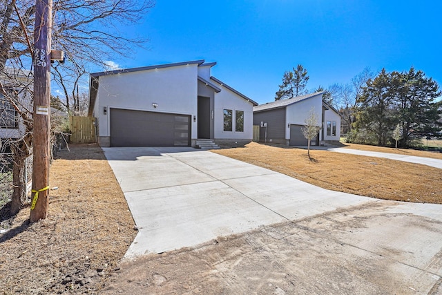 view of front facade with concrete driveway, fence, an attached garage, and stucco siding