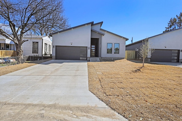 view of front of property with a garage, driveway, fence, and stucco siding