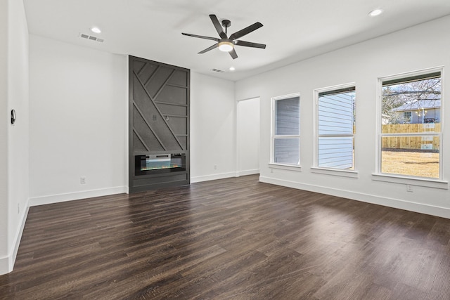 interior space with ceiling fan, a large fireplace, wood finished floors, visible vents, and baseboards