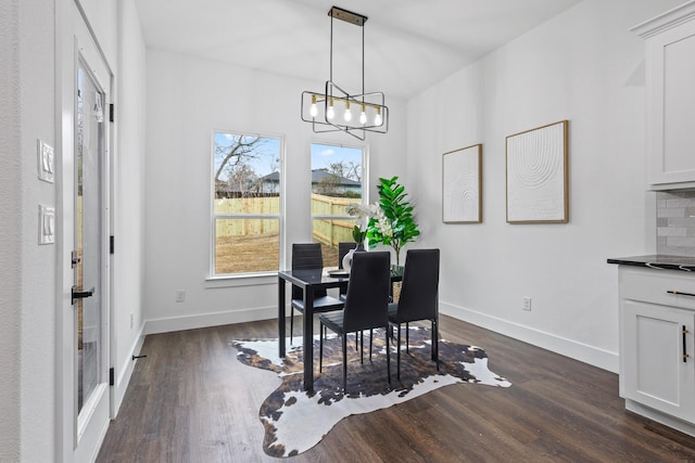 dining space with dark wood-style floors, baseboards, and an inviting chandelier