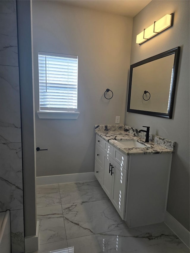 bathroom with marble finish floor, vanity, and baseboards