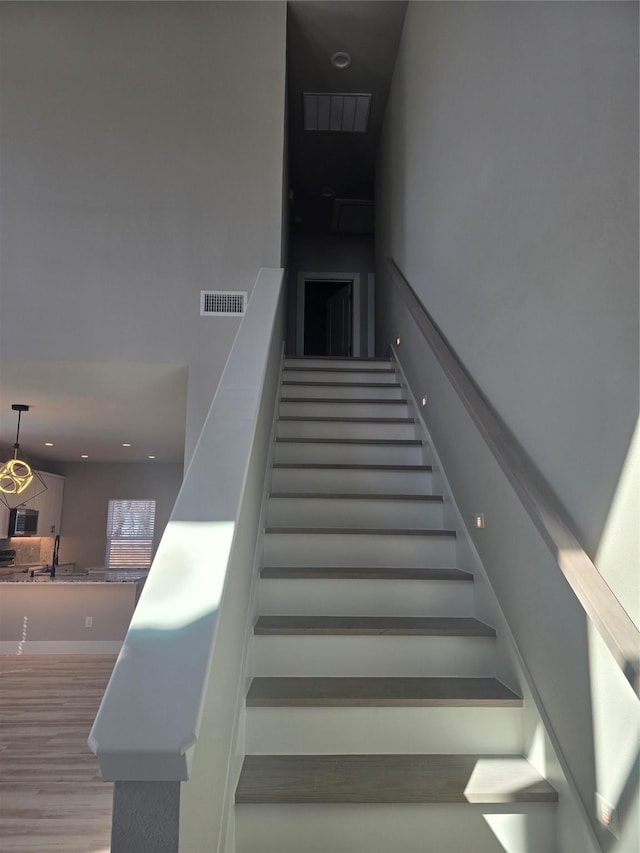 stairway featuring wood finished floors and visible vents