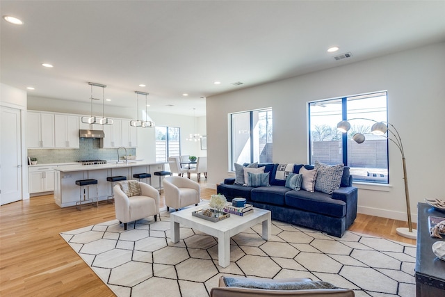 living room with light wood-type flooring, visible vents, and recessed lighting