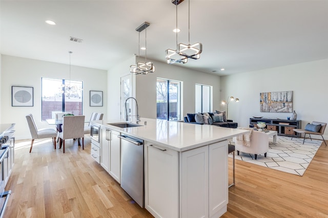 kitchen with light countertops, hanging light fixtures, appliances with stainless steel finishes, white cabinets, and a sink