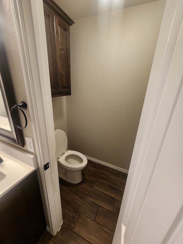 bathroom with vanity, wood finished floors, toilet, and baseboards