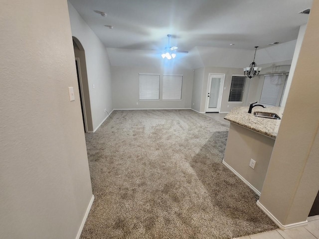 unfurnished living room with arched walkways, light carpet, vaulted ceiling, a sink, and baseboards