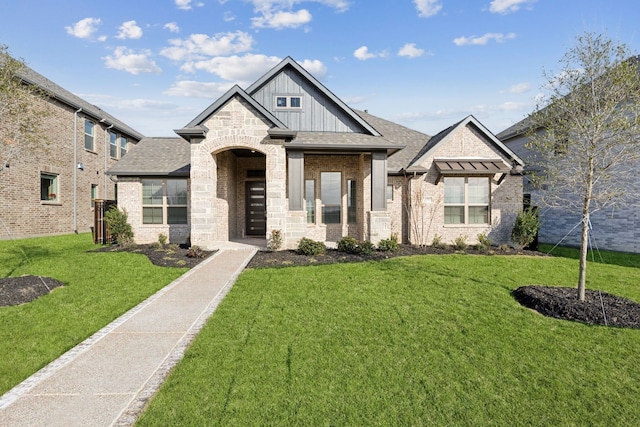 view of front of home featuring board and batten siding, a front yard, brick siding, and a shingled roof