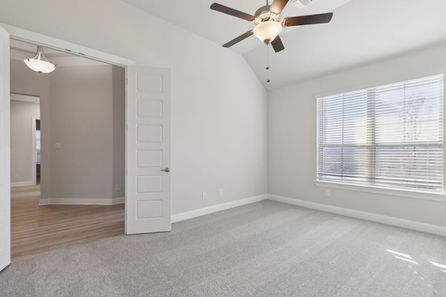 empty room with a ceiling fan, carpet, vaulted ceiling, and baseboards