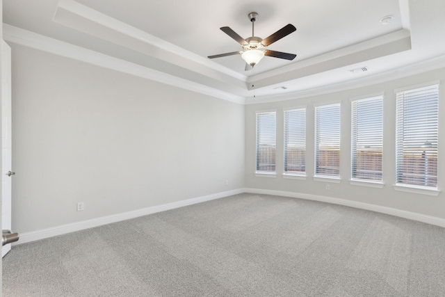 empty room with ornamental molding, a raised ceiling, and baseboards