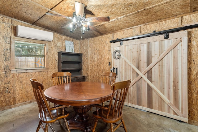 dining room with concrete floors, a wall mounted air conditioner, a barn door, and a ceiling fan