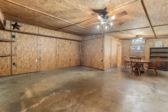 below grade area featuring wood walls and ceiling fan