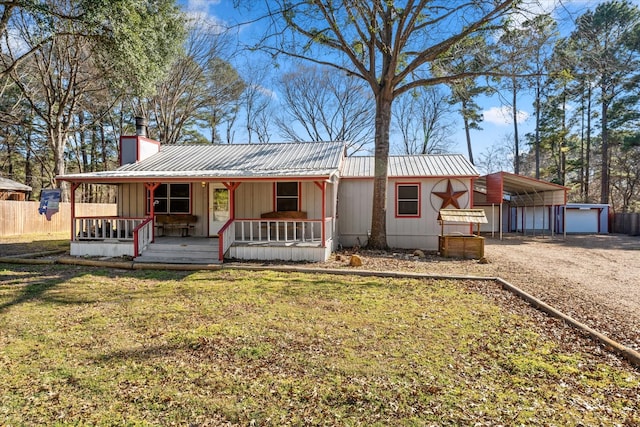ranch-style home featuring covered porch, dirt driveway, a chimney, metal roof, and a detached carport