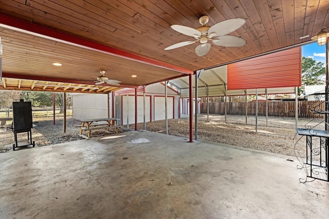 view of patio / terrace with a ceiling fan, an outbuilding, fence, and a carport