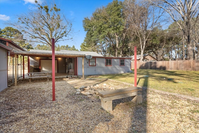 back of house featuring metal roof, fence, and a lawn