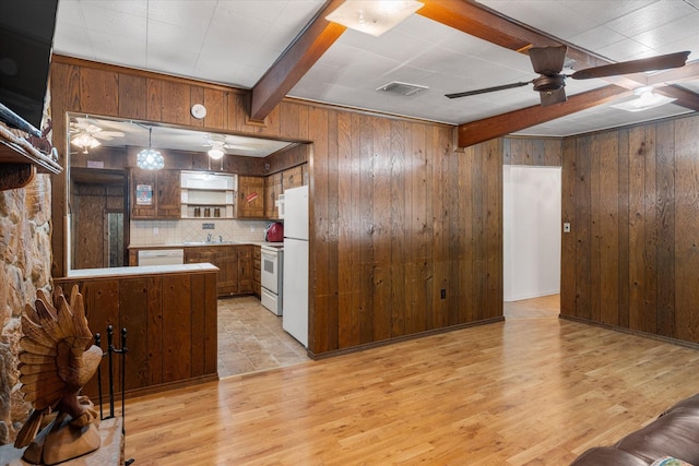 kitchen featuring ceiling fan, wooden walls, and white appliances