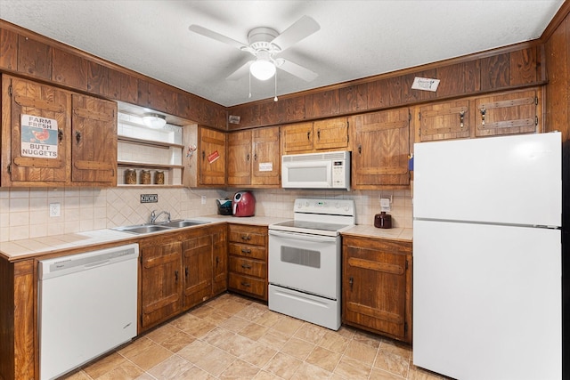 kitchen with a ceiling fan, white appliances, a sink, tile counters, and tasteful backsplash