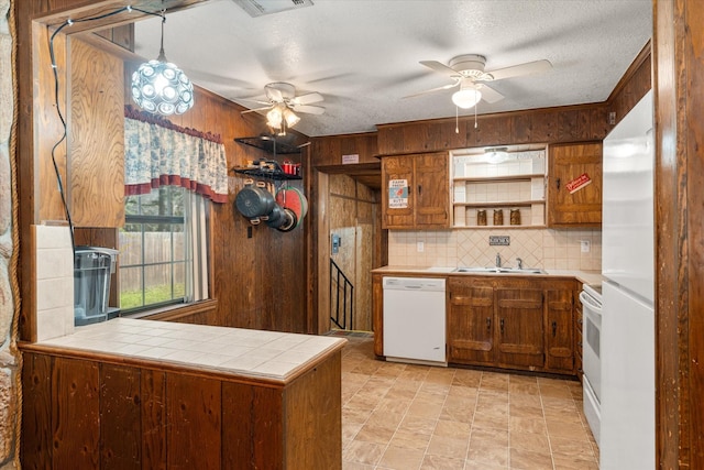 kitchen with a ceiling fan, a sink, open shelves, wood walls, and white appliances