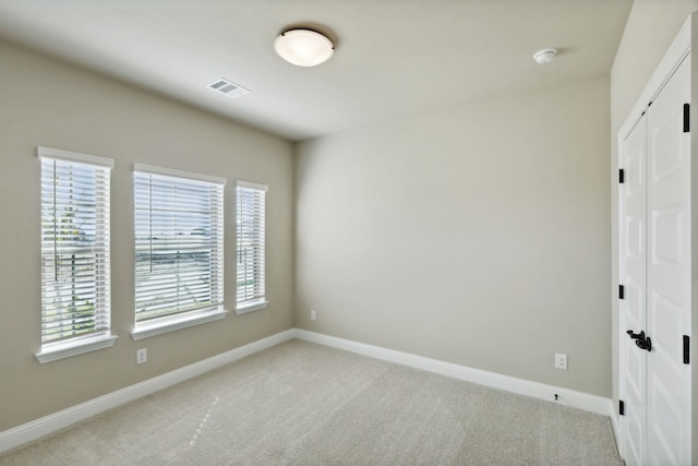 unfurnished room featuring baseboards, visible vents, and light colored carpet