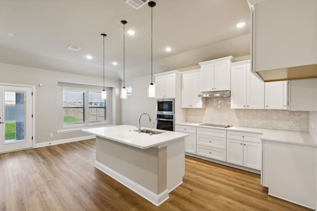 kitchen with light countertops, white cabinetry, a sink, built in microwave, and oven