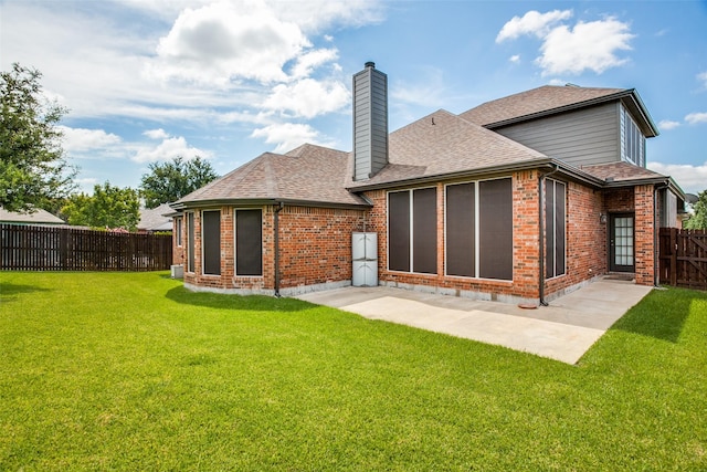 rear view of house featuring brick siding, a shingled roof, fence, and a yard