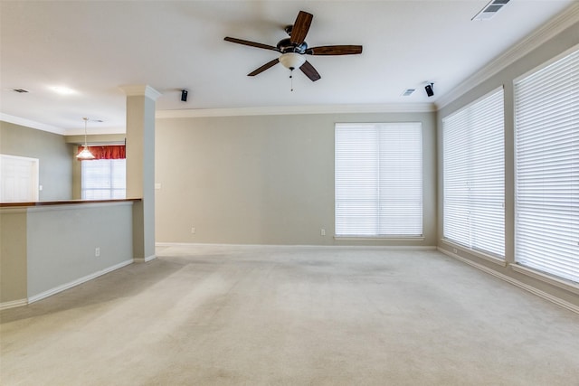 unfurnished room featuring light colored carpet, a ceiling fan, baseboards, visible vents, and crown molding